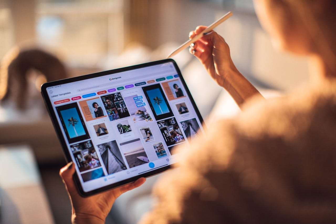 about-us A person uses a digital tablet with a stylus indoors in a warm, cozy setting.