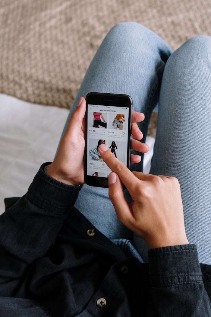 services-02 Close-up of a woman shopping online on a smartphone while relaxing at home.