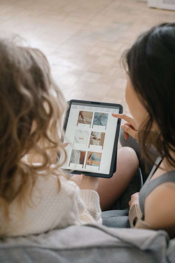 who-we-are Two women sitting together, shopping online using a tablet, sharing ideas and browsing products.